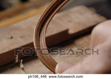 Stock Photograph - Carpenter's hands bending a shaved strip of wood. Fotosearch