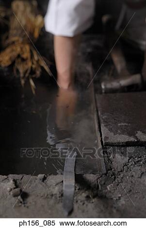 Close-up of a blacksmith's hand dipping a metal rod into water View Large Photo Image Stock Photography - Close-up of a blacksmith's hand dipping a metal rod into water. Fotosearch