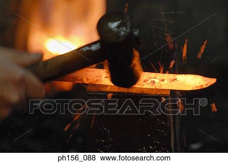 Stock Photo - Close-up of a blacksmith's hand hitting a heated metal rod with a hammer. Fotosearch
