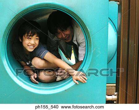 Close-up of a boy sitting in a hollow tube with his father View Large Photo Image Stock Image - Close-up of a boy sitting in a hollow tube with his father. Fotosearch