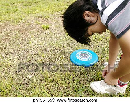 Stock Photo - Close-up of a boy tying his shoe laces. Fotosearch