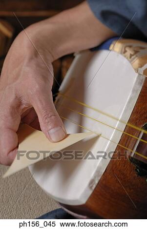 Stock Photography - Close-up of a carpenter's hand holding a stringed instrument. Fotosearch