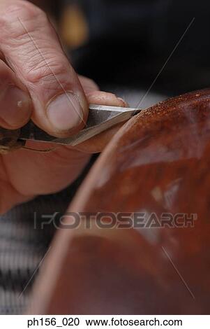 Stock Image - Close-up of a carpenter's hand sharpening a wooden structure. Fotosearch