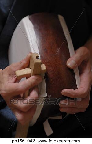 Stock Image - Close-up of a carpenter's hands making a samisen. Fotosearch