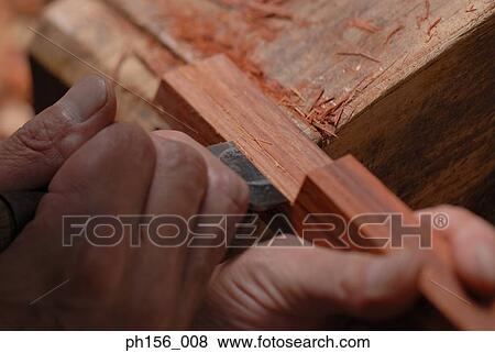 Close-up of a carpenter's hands peeling wood with a chisel View Large Photo Image Stock Photo - Close-up of a carpenter's hands peeling wood with a chisel. Fotosearch