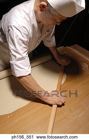 Stock Image - Close-up of a chef rolling dough. Fotosearch