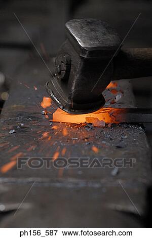 Stock Photo - Close-up of a hammer hitting a heated metal rod. Fotosearch