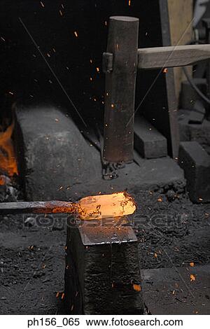 Stock Photography - Close-up of a hammer hitting a heated metal rod. Fotosearch