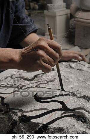Stock Image - Close-up of a human hand drawing on a rock. Fotosearch