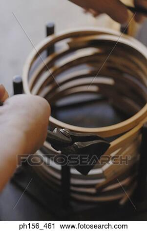 Stock Image - Close-up of a human hand making a wooden basket. Fotosearch