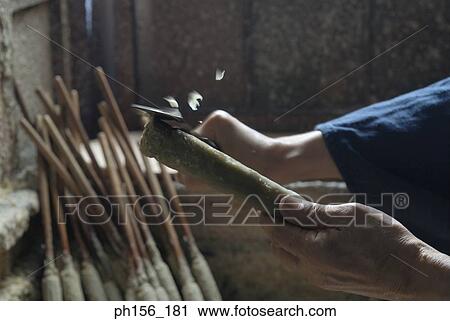 Stock Image - Close-up of a man's hand peeling a stick on a candle. Fotosearch