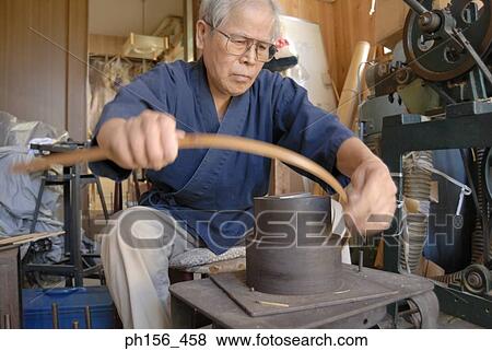 Stock Photo - Close-up of a mature man bending bamboo strips. Fotosearch