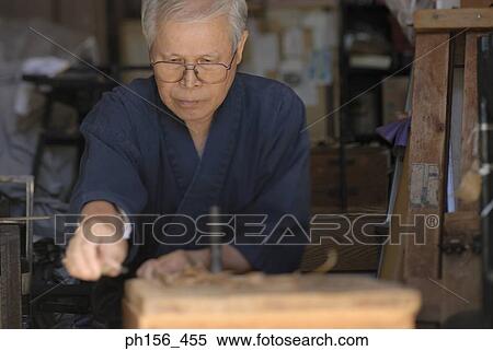Stock Photography - Close-up of a mature man shaving a wooden stick. Fotosearch