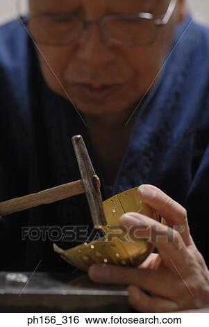 Stock Photograph - Close-up of a person making a metal bowl with a hammer. Fotosearch