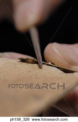Stock Photograph - Close-up of a person's fingers sharpening a blade with a rasp. Fotosearch