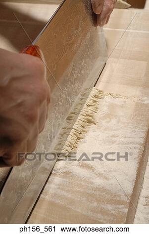 Close-up of a person's hand cutting raw noodles View Large Photo Image Stock Image - Close-up of a person's hand cutting raw noodles. Fotosearch