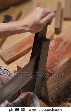 Close-up of a person's hand cutting wood with a saw View Large Photo Image Stock Image - Close-up of a person's hand cutting wood with a saw. Fotosearch