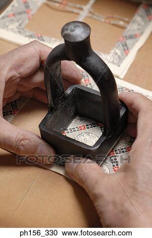 Stock Image - Close-up of a person's hand cutting cardboard with a work tool. Fotosearch