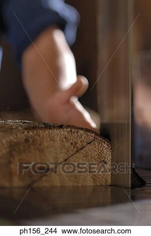Picture - Close-up of a person's hand holding a block of wood in a workshop. Fotosearch