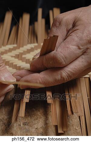 Stock Image - Close-up of a person's hand making a basket. Fotosearch