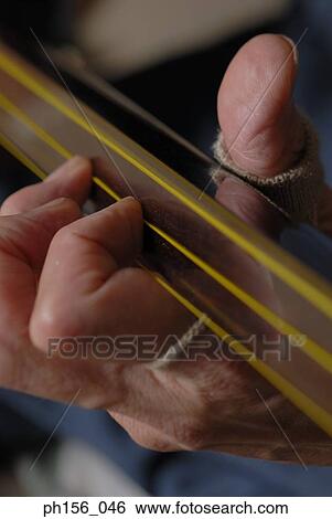 Stock Photograph - Close-up of a person's hand playing a samisen. Fotosearch