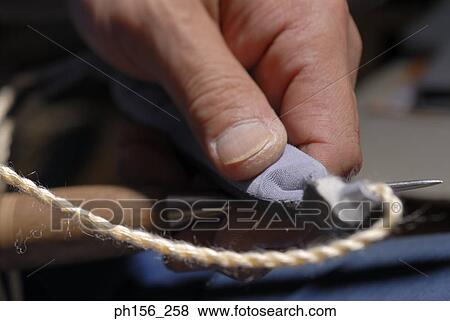 Stock Photo - Close-up of a person's hand sewing with a needle. Fotosearch