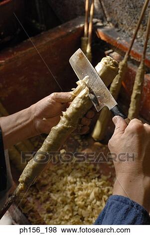 Stock Photo - Close-up of a person's hand shaping a candle with a knife. Fotosearch
