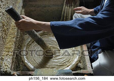 Picture - Close-up of a person's hand stirring wax in a container. Fotosearch