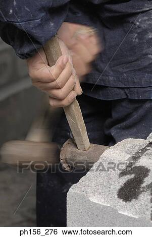 Close-up of a person's hand using hammers on a stone View Large Photo Image Stock Photograph - Close-up of a person's hand using hammers on a stone. Fotosearch