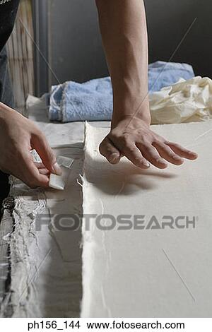 Picture - Close-up of a person's hands cutting a sheet of paper with the help of a comb. Fotosearch