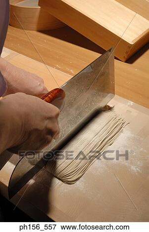 Stock Photo - Close-up of a person's hands cutting noodles. Fotosearch