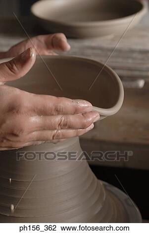 Stock Image - Close-up of a person's hands making pottery. Fotosearch