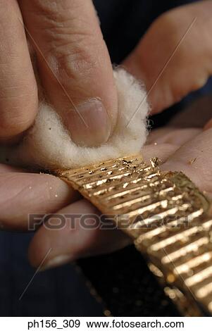 Stock Photo - Close-up of a person's hands rubbing a chain with cotton. Fotosearch