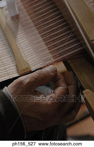 Stock Photo - Close-up of a person's hands working on a loom. Fotosearch