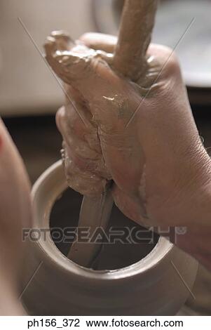 Stock Image - Close-up of a potter's hand holding a stick and making pottery. Fotosearch
