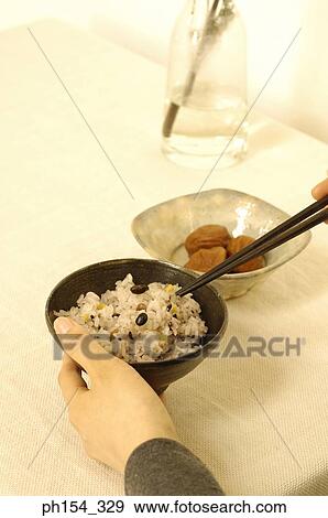 Stock Photo - Close-up of a woman's hand holding a bowl of rice. Fotosearch