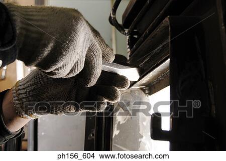 Picture - Close-up of a worker's hand closing the door of a furnace. Fotosearch