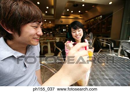 Close-up of a young couple sitting together in a restaurant and smiling View Large Photo Image Stock Photo - Close-up of a young couple sitting together in a restaurant and smiling. Fotosearch