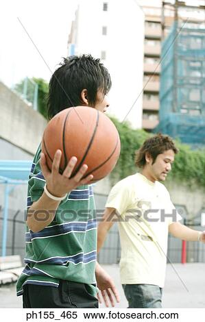 Stock Photography - Close-up of a young man holding a basketball with a young man standing beside him. Fotosearch