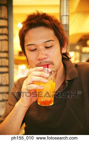 Close-up of a young man sipping juice View Large Photo Image Stock Image - Close-up of a young man sipping juice. Fotosearch