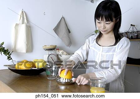 Close-up of a young woman squeezing an orange on a juicer View Large Photo Image Stock Image - Close-up of a young woman squeezing an orange on a juicer. Fotosearch