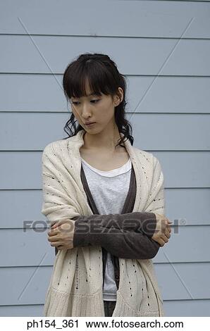 Stock Image - Close-up of a young woman standing with her arms crossed. Fotosearch