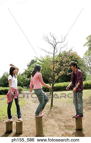Close-up of two young women and a young man standing on cement posts View Large Photo Image Stock Photograph - Close-up of two young women and a young man standing on cement posts. Fotosearch