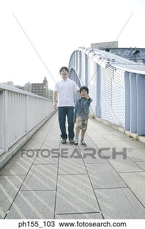 Father and his son walking on a bridge View Large Photo Image Stock Image - Father and his son walking on a bridge. Fotosearch