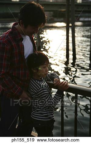 Father standing with his son eating candy View Large Photo Image Stock Photo - Father standing with his son eating candy. Fotosearch