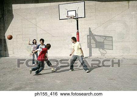 Stock Photograph - Four young men and a young woman playing basketball. Fotosearch