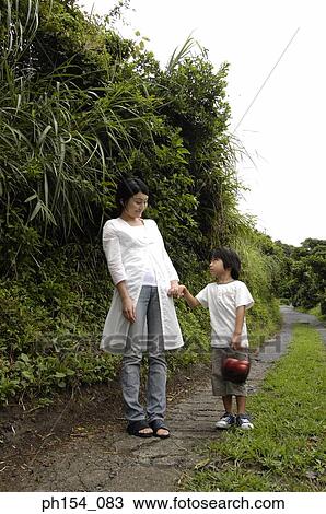 Girl holding a basket of apples and standing with her mother View Large Photo Image Stock Image - Girl holding a basket of apples and standing with her mother. Fotosearch