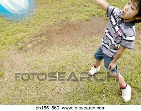 Stock Image - High angle view of a boy playing with a plastic disc. Fotosearch