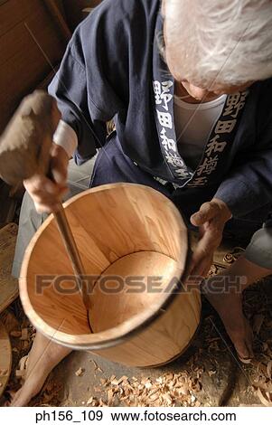 Stock Photo - High angle view of a carpenter hitting a barrel with a mallet. Fotosearch