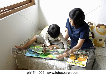 Stock Photograph - High angle view of a mid adult woman teaching her daughter. Fotosearch